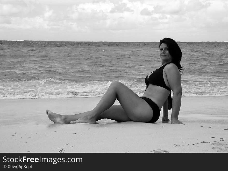 Beautiful, brunette swimsuit model in classic black and white posing on the white sands of the Caribbean.