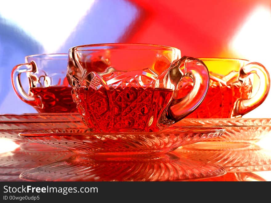 Close-up of glass teacup and saucer against multi colored abstract background. Close-up of glass teacup and saucer against multi colored abstract background