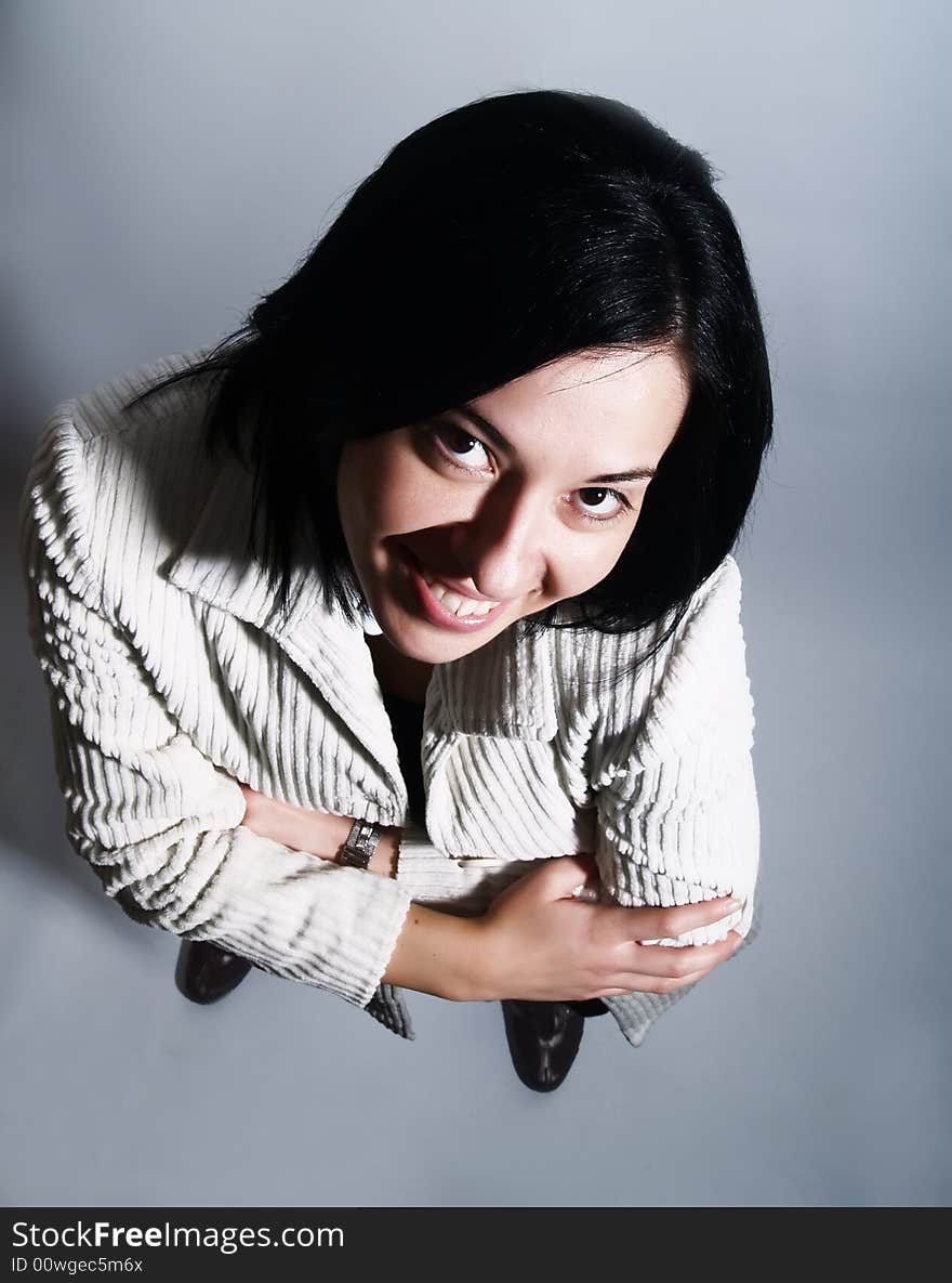 A high-key portrait about a young pretty lady with black hair who is looking up and she is smiling. She is wearing a white coat and a black dress. A high-key portrait about a young pretty lady with black hair who is looking up and she is smiling. She is wearing a white coat and a black dress.