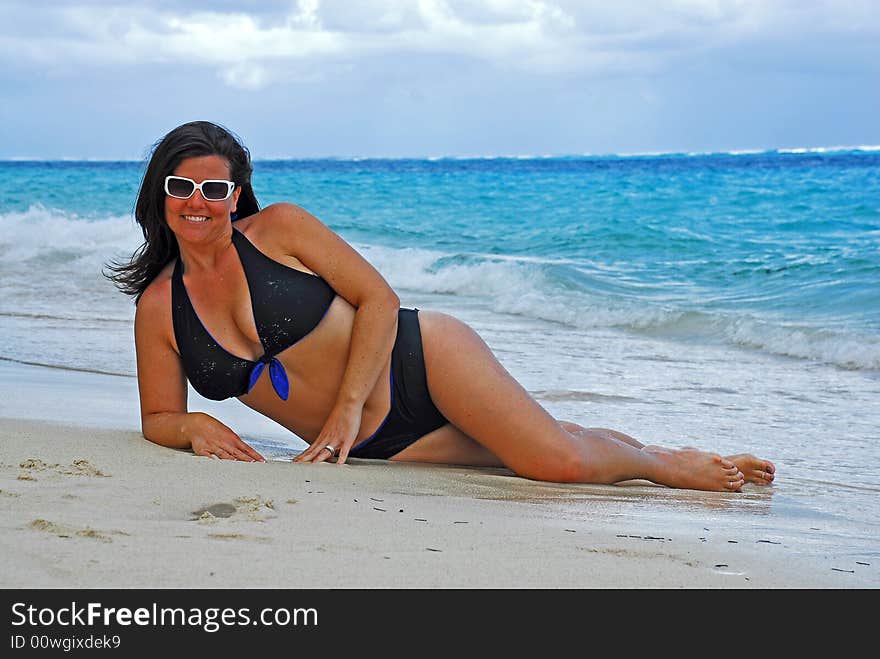 Beautiful swimsut model posing on the white sand of the Caribbean with her trendy white sun glasses. Beautiful swimsut model posing on the white sand of the Caribbean with her trendy white sun glasses.