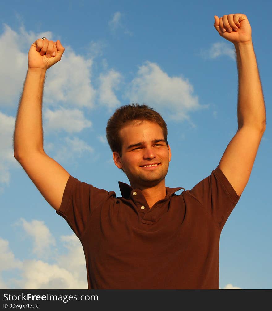 Man with his arms raised and a blue sky background. Man with his arms raised and a blue sky background.