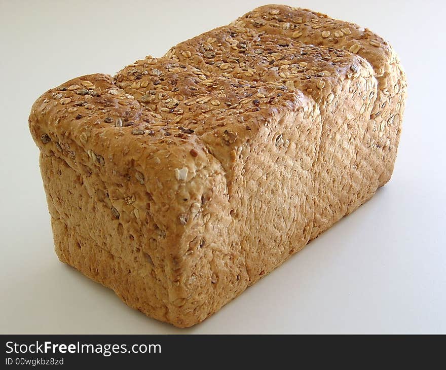 A large healthy loaf of brown bread just waiting to be sliced and eaten.