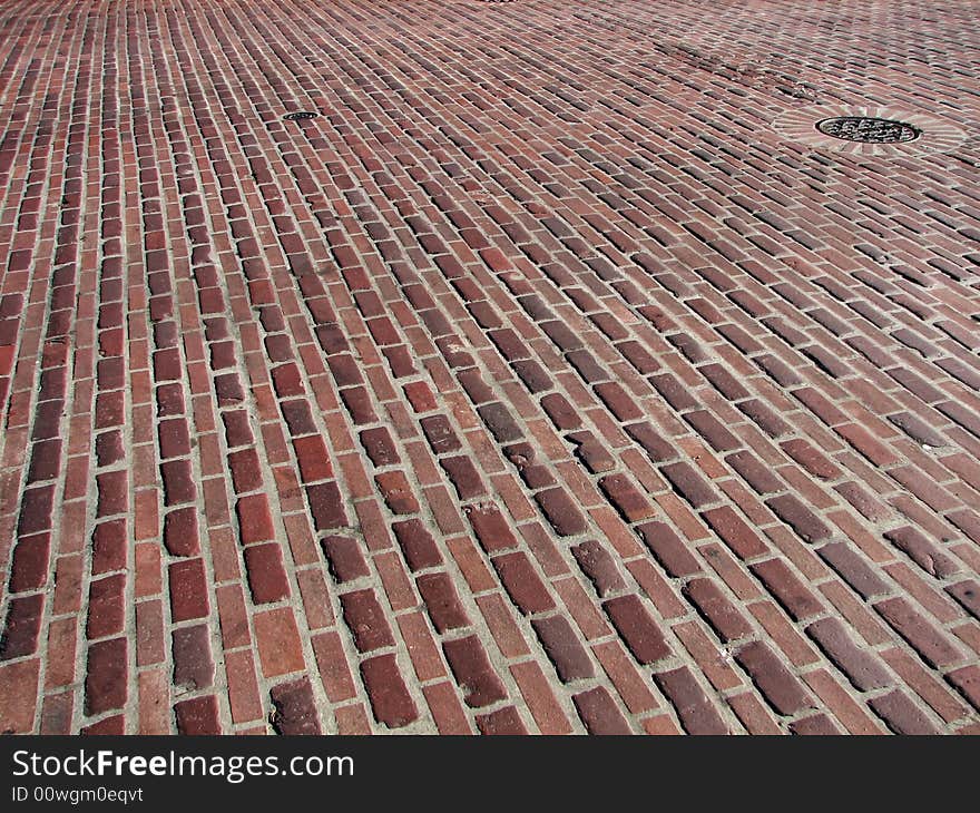 A red brick road with a drain in the upper right corner