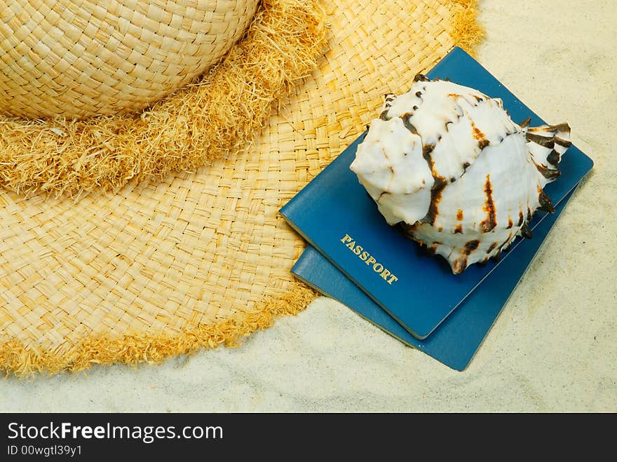 Straw hat, seashell and passports on the coral sand