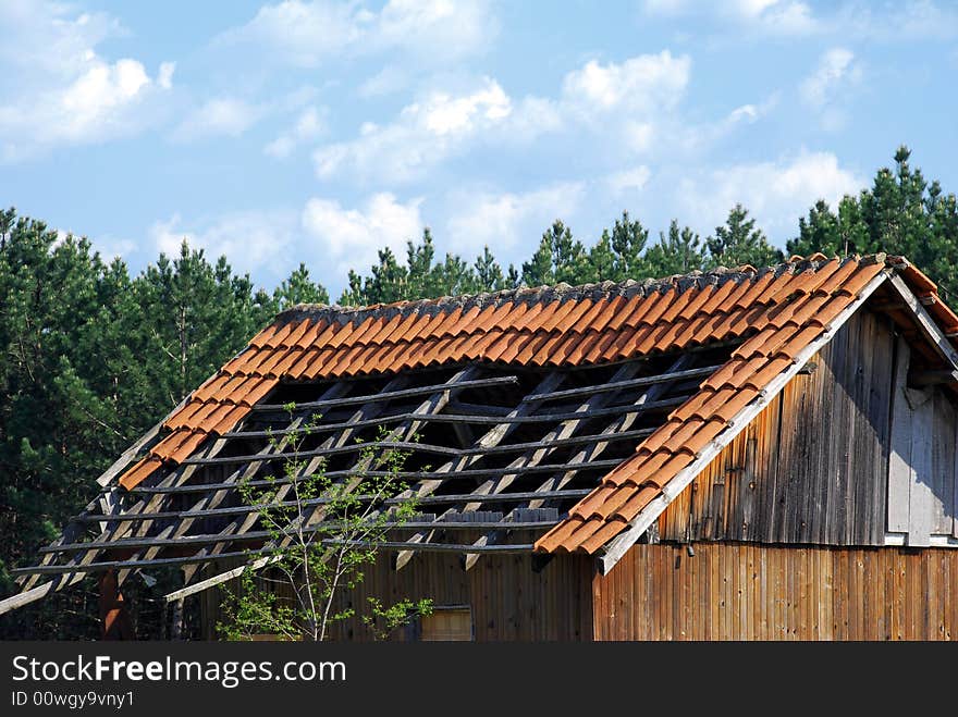 Old small house roof details over pine trees and blue sky. Old small house roof details over pine trees and blue sky