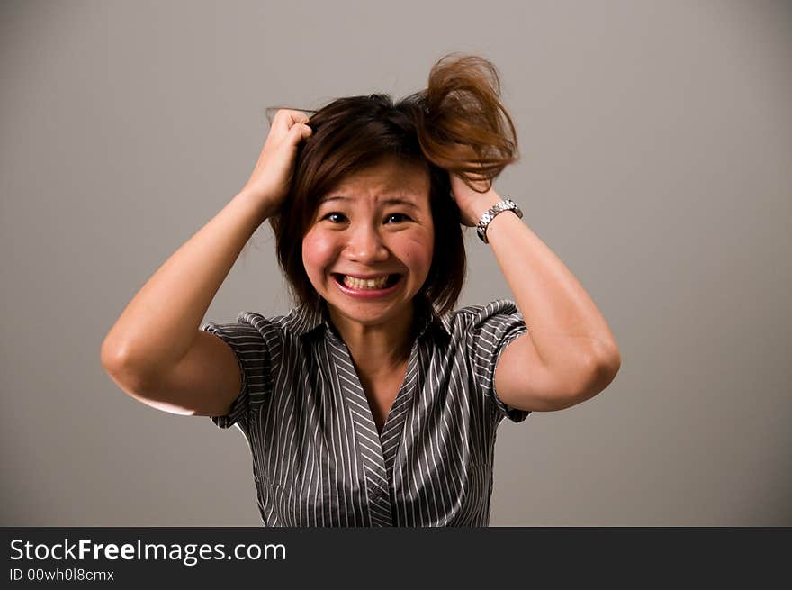 Asian lady in business attire, feeling very frustrated, tearing her hair out. Asian lady in business attire, feeling very frustrated, tearing her hair out