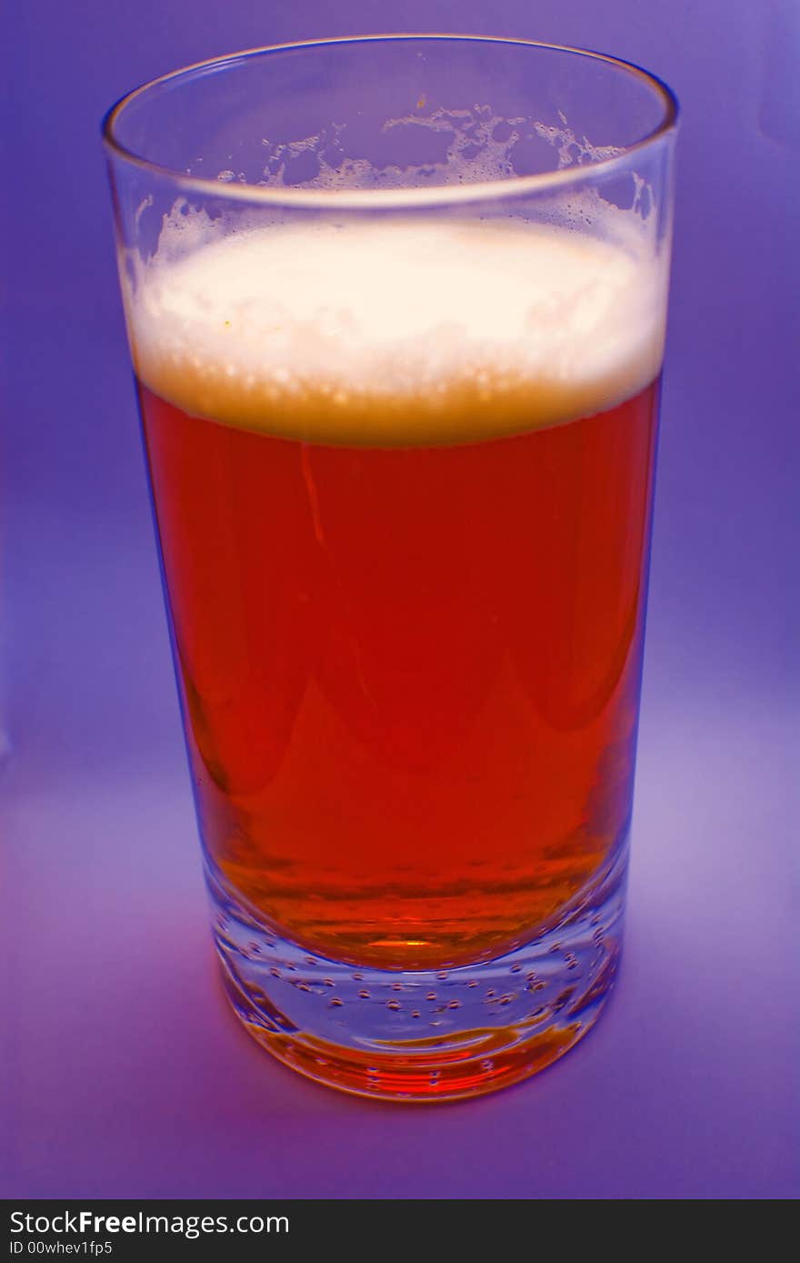 A glass of beer with purple background. A glass of beer with purple background