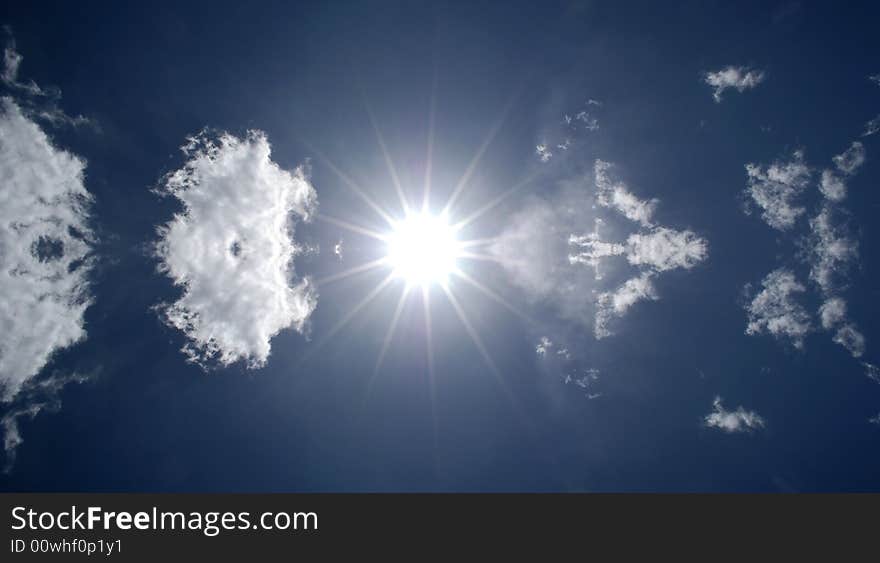 Blazing hot sun shining in blue sky with clouds