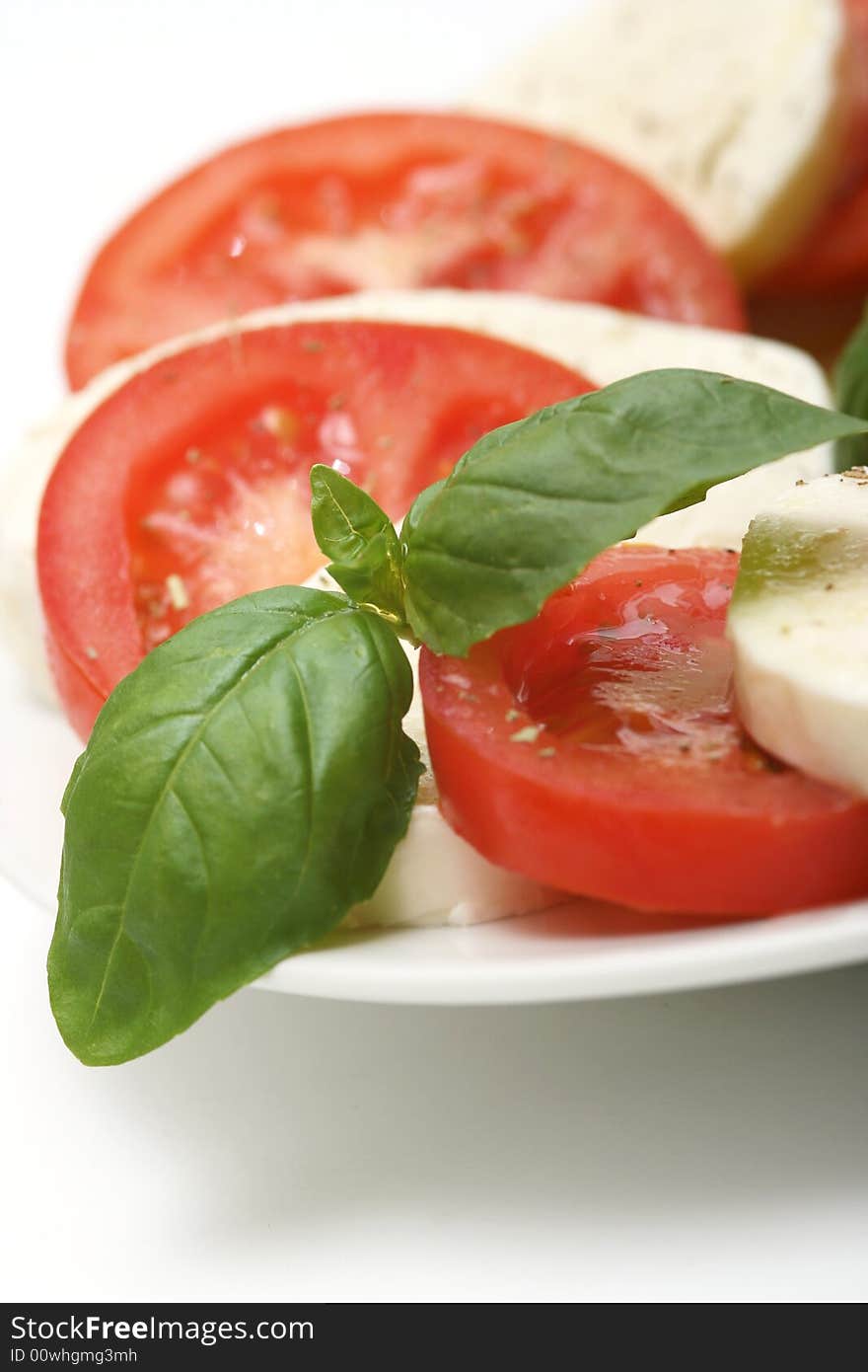 Close up of mozzarella tricolor salad with tomatoes and basil with drizzling of olive oil. Close up of mozzarella tricolor salad with tomatoes and basil with drizzling of olive oil.