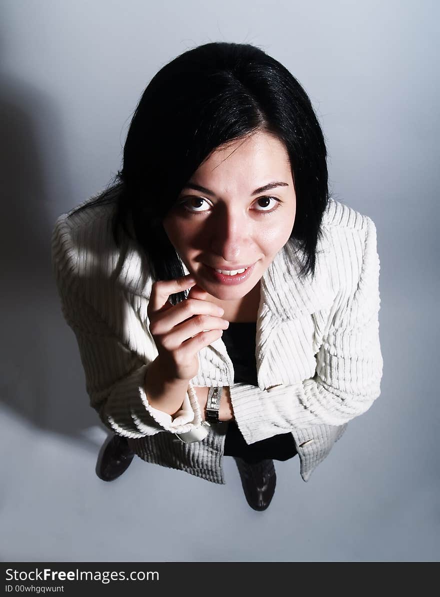 A portrait from above about a young pretty lady with black hair who is looking up and she is smiling. She is wearing a white coat and a black dress. A portrait from above about a young pretty lady with black hair who is looking up and she is smiling. She is wearing a white coat and a black dress.