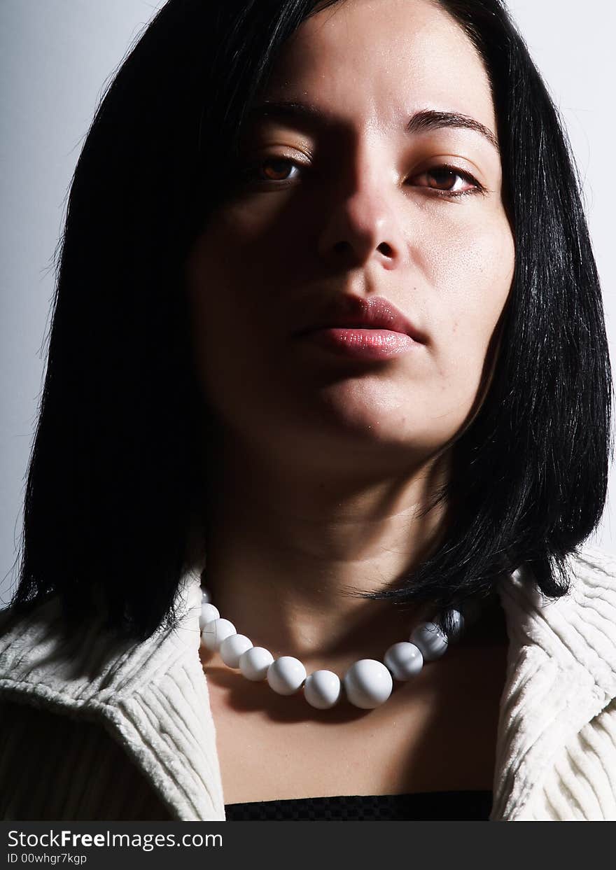 A high-key portrait about an attractive lady with black hair who is looking ahead and she has a glamorous look. She is wearing a white coat, a black dress and a white necklace. A high-key portrait about an attractive lady with black hair who is looking ahead and she has a glamorous look. She is wearing a white coat, a black dress and a white necklace.