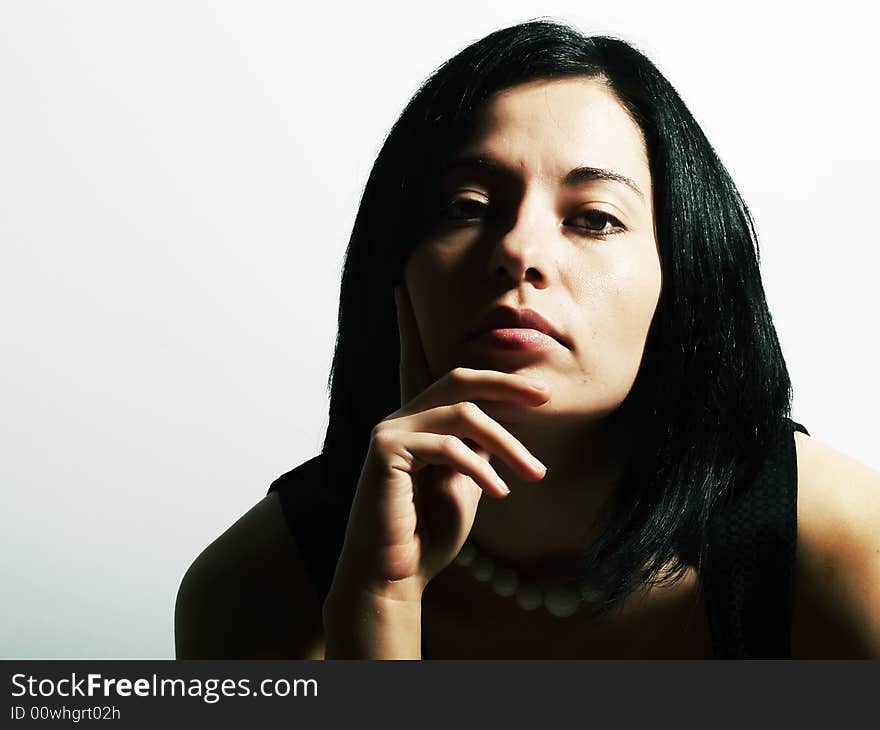 A portrait about an attractive trendy girl with black hair who is looking ahead and she has a charming look. She is wearing a black dress and a white necklace. A portrait about an attractive trendy girl with black hair who is looking ahead and she has a charming look. She is wearing a black dress and a white necklace.