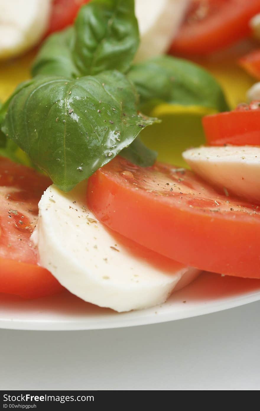 Close up of mozzarella tricolore salad with tomatoes and basil with drizzling of olive oil. Close up of mozzarella tricolore salad with tomatoes and basil with drizzling of olive oil.