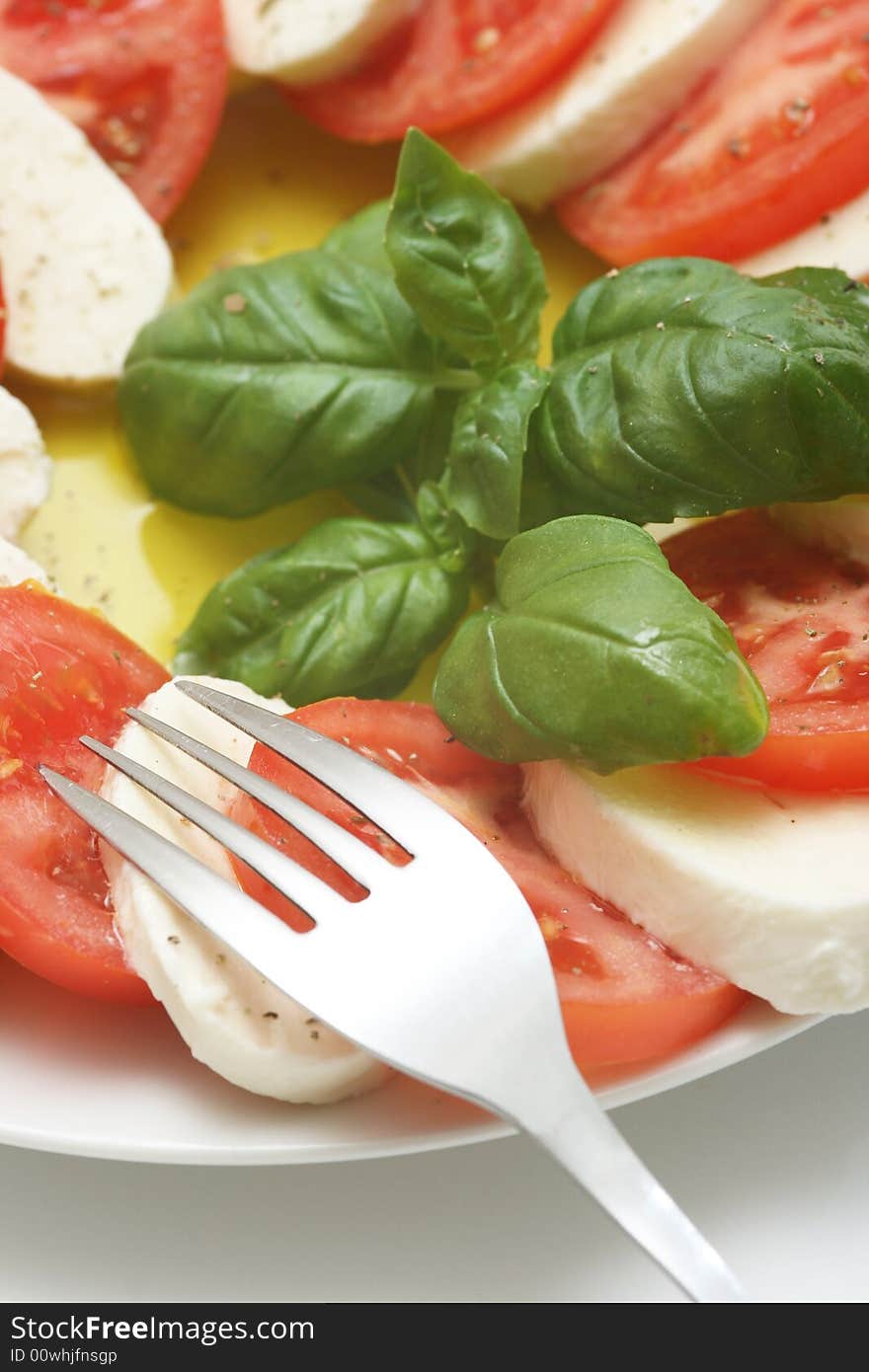 Close up of mozzarella tricolore salad with tomatoes and basil with drizzling of olive oil. Close up of mozzarella tricolore salad with tomatoes and basil with drizzling of olive oil.