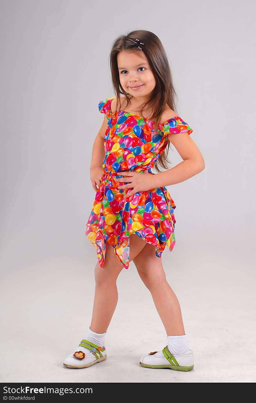 Little cute brown-haired baby girl posing in fancy-colored short dress. Little cute brown-haired baby girl posing in fancy-colored short dress