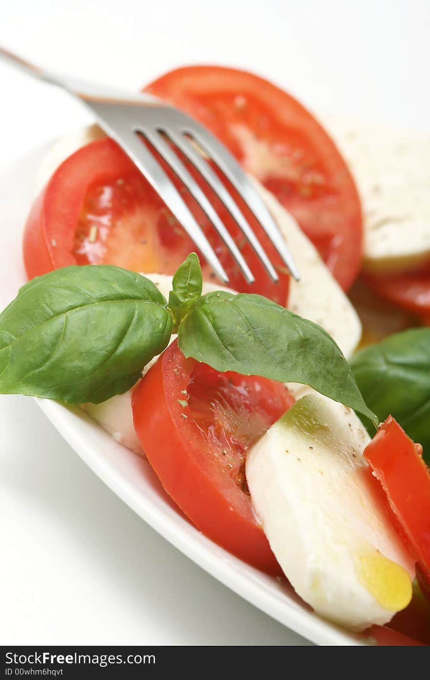 Close up of mozzarella tricolore salad with tomatoes and basil with drizzling of olive oil. Close up of mozzarella tricolore salad with tomatoes and basil with drizzling of olive oil.