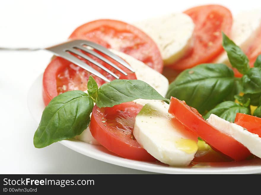 Close up of mozzarella tricolore salad with tomatoes and basil with drizzling of olive oil. Close up of mozzarella tricolore salad with tomatoes and basil with drizzling of olive oil.