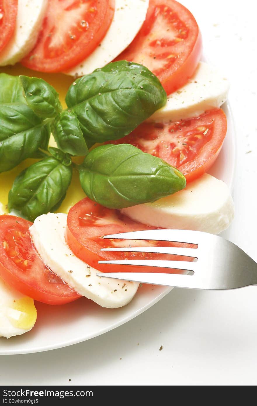 Close up of mozzarella tricolore salad with tomatoes and basil with drizzling of olive oil. Close up of mozzarella tricolore salad with tomatoes and basil with drizzling of olive oil.