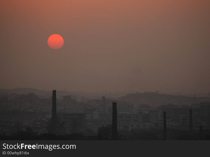 Modern city's sunset with foul air, some chimneys on foreground, Guangzhou, China,2008.