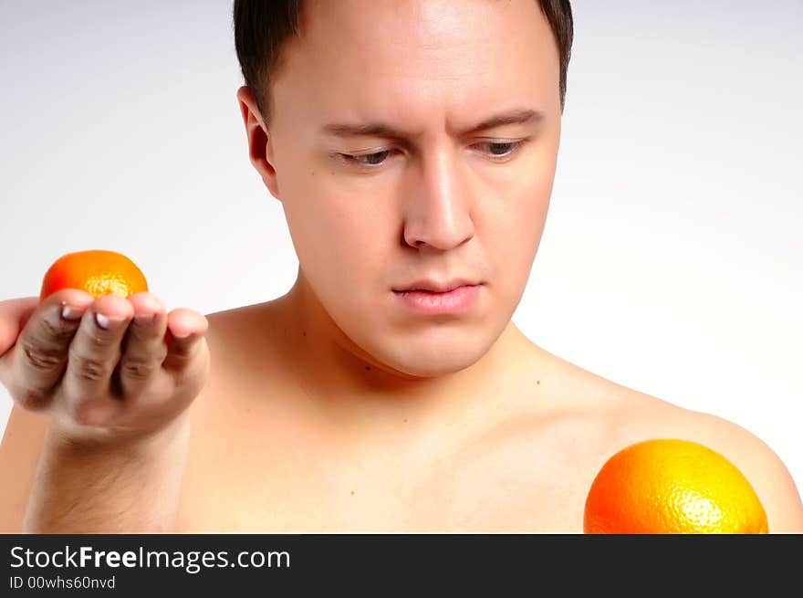 Man with two fresh bright oranges makes a choice. Man with two fresh bright oranges makes a choice