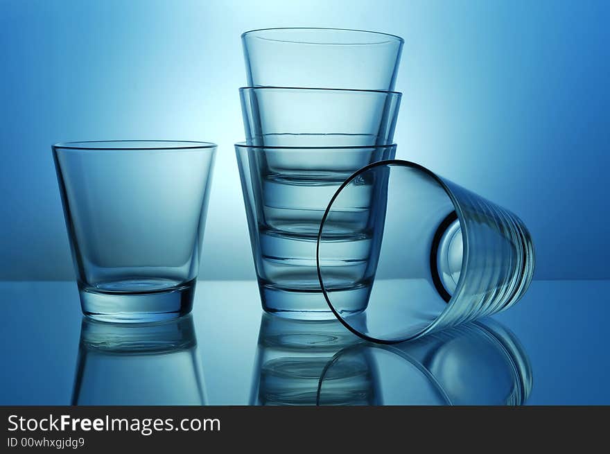 Stack of empty shots for tequila or juice on blue background. Stack of empty shots for tequila or juice on blue background