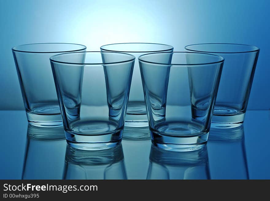 Group of empty shots for tequila or juice on blue background. Group of empty shots for tequila or juice on blue background