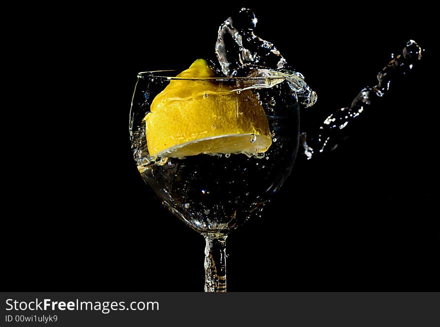 Piece of lemon falling in a glass making a big splash. Piece of lemon falling in a glass making a big splash