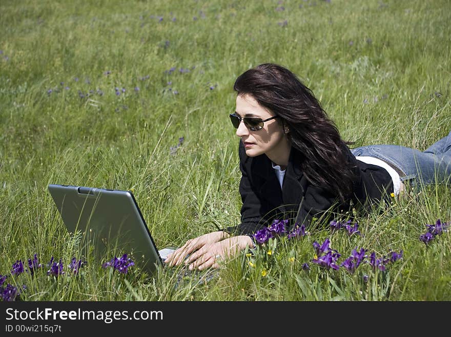 Woman laying down on grass with laptop. Woman laying down on grass with laptop