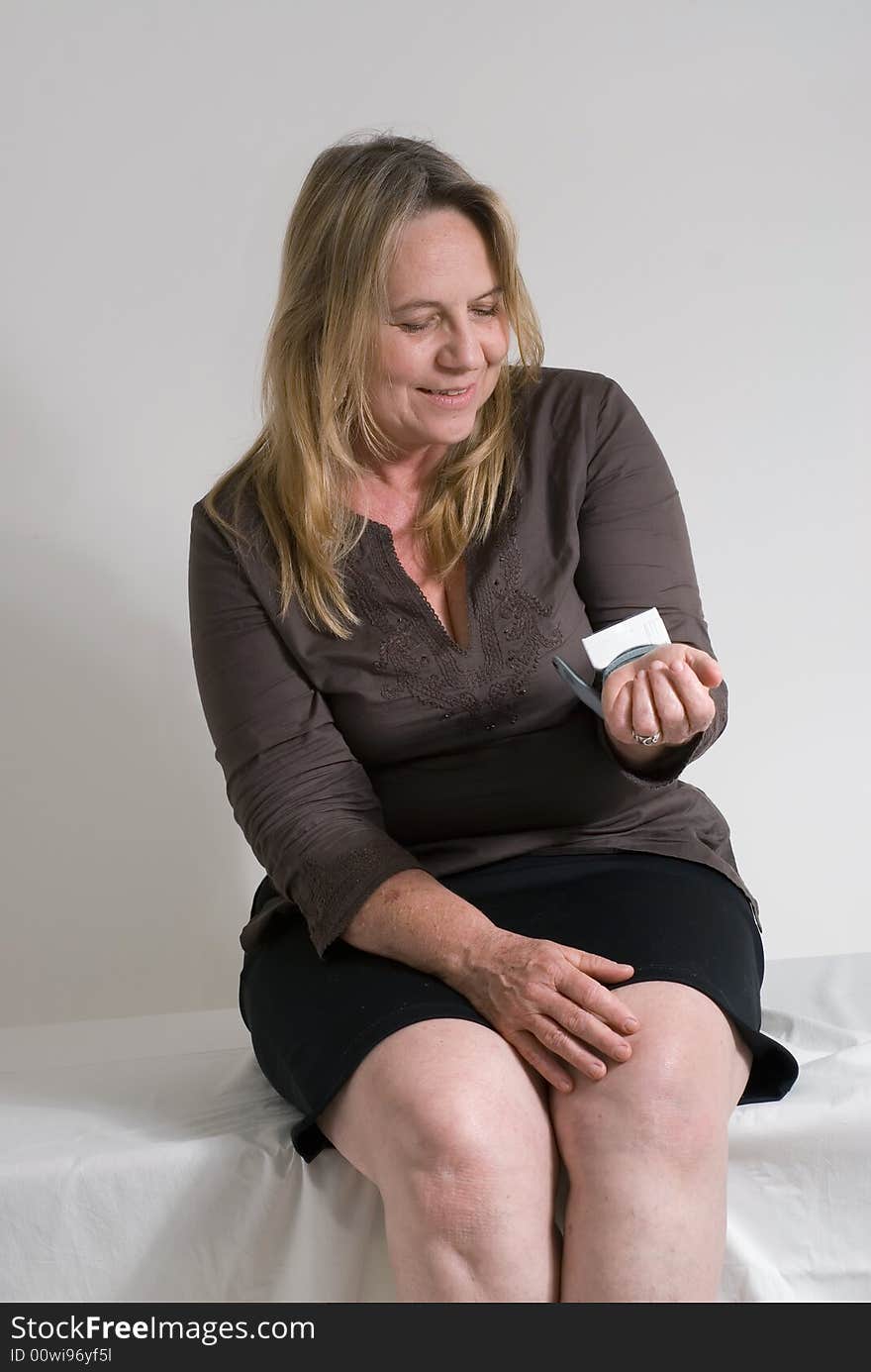 An isolated shot of a middle-aged female sitting on a exam table having her blood pressure taken by a machine. An isolated shot of a middle-aged female sitting on a exam table having her blood pressure taken by a machine.