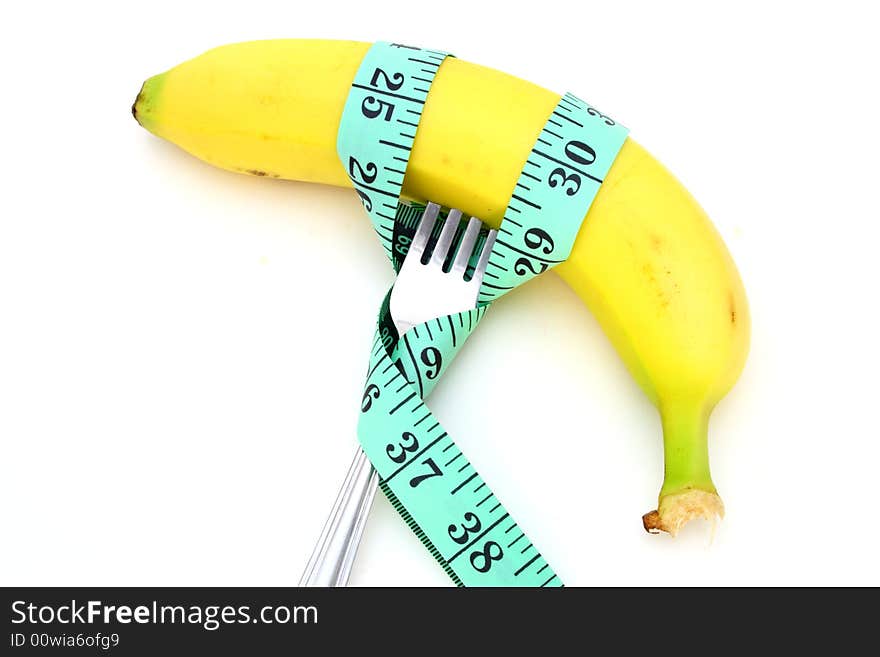 Green tape measure wrapped around a banana and a fork. Green tape measure wrapped around a banana and a fork