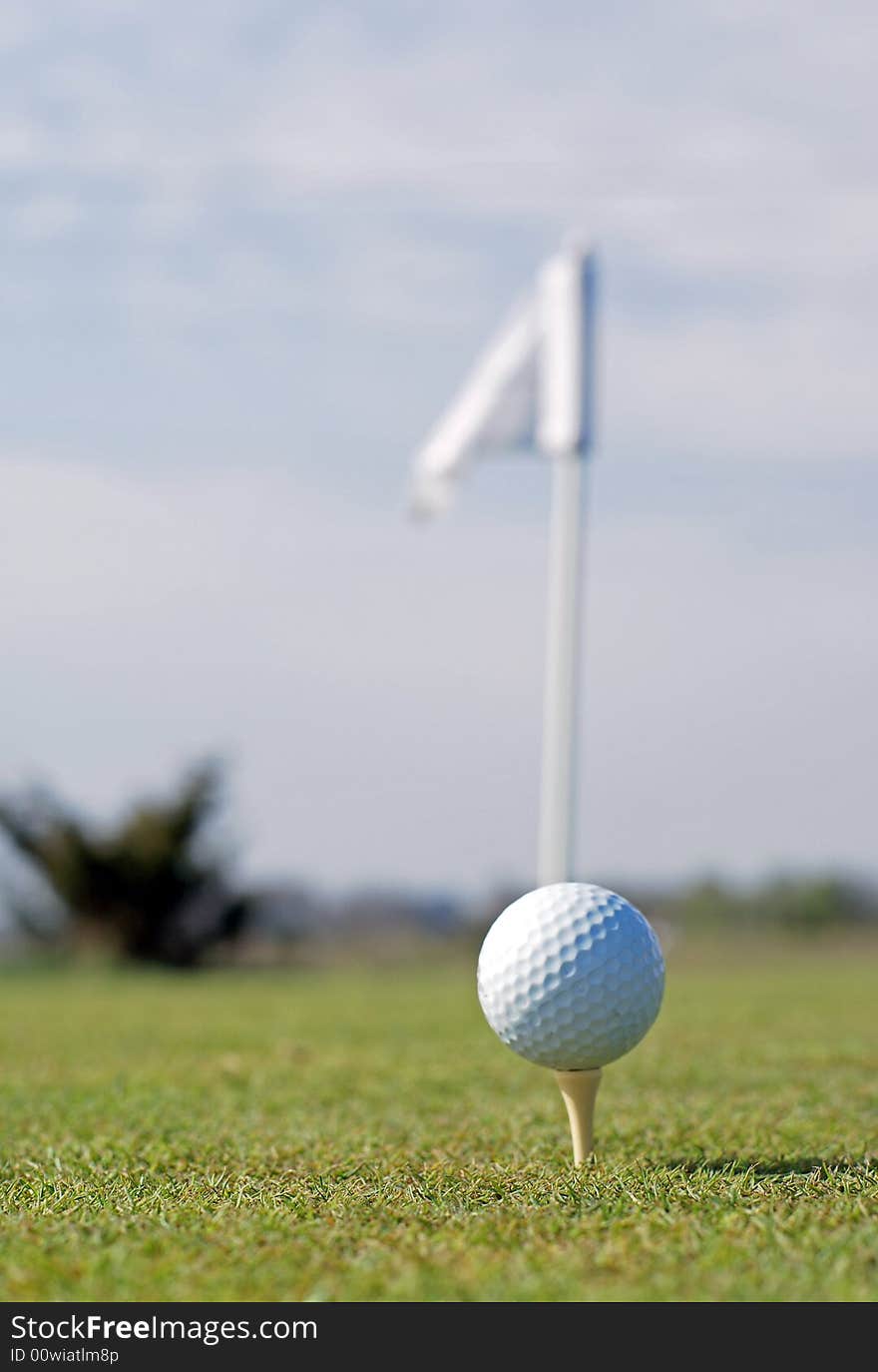 Golf ball in tall green grass set against blue sky