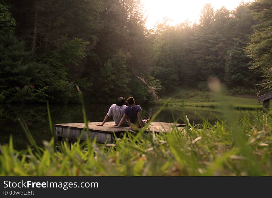 Couple sitting on dock waiting for sunset. Couple sitting on dock waiting for sunset