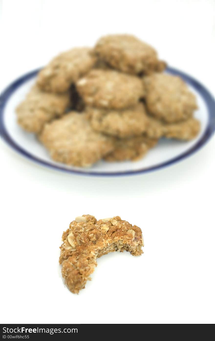 Plate of homemade oatmeal cookies and one cookie with a bite taken out of it. Plate of homemade oatmeal cookies and one cookie with a bite taken out of it