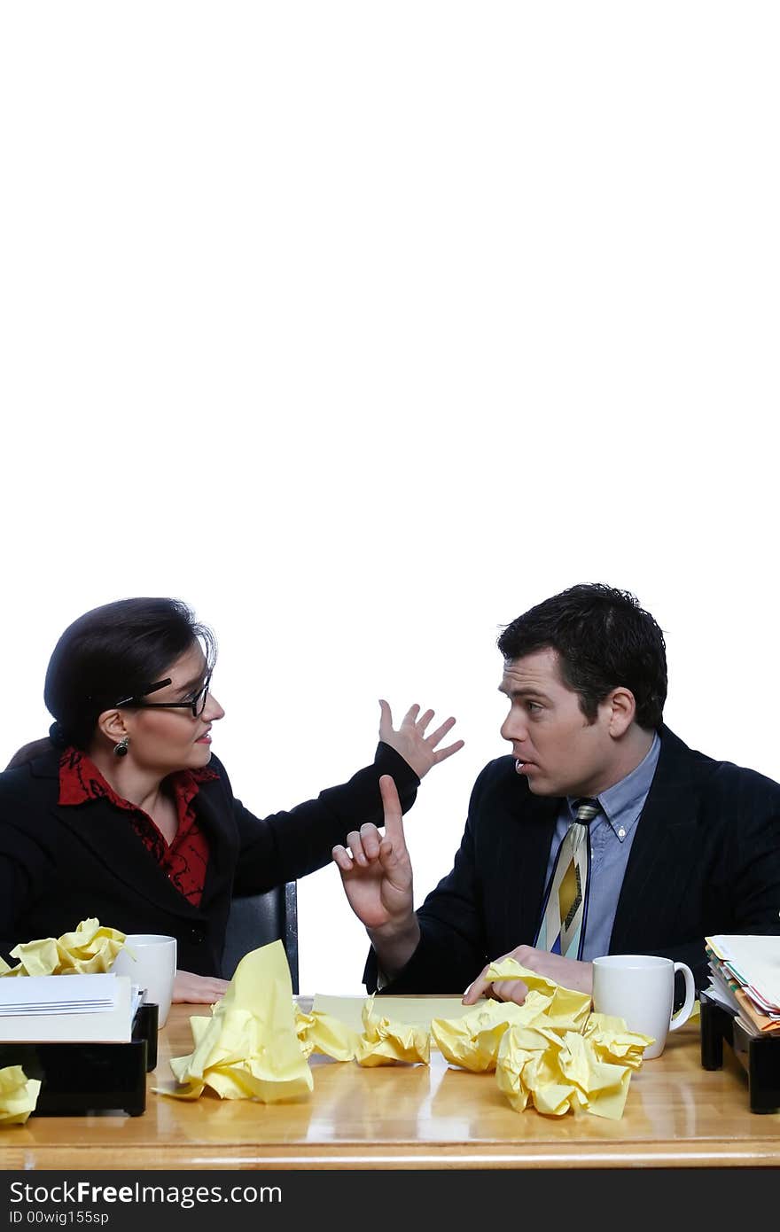 An isolated shot of a businessman and businesswoman discussing ideas at a desk, littered with yellow paper. An isolated shot of a businessman and businesswoman discussing ideas at a desk, littered with yellow paper.