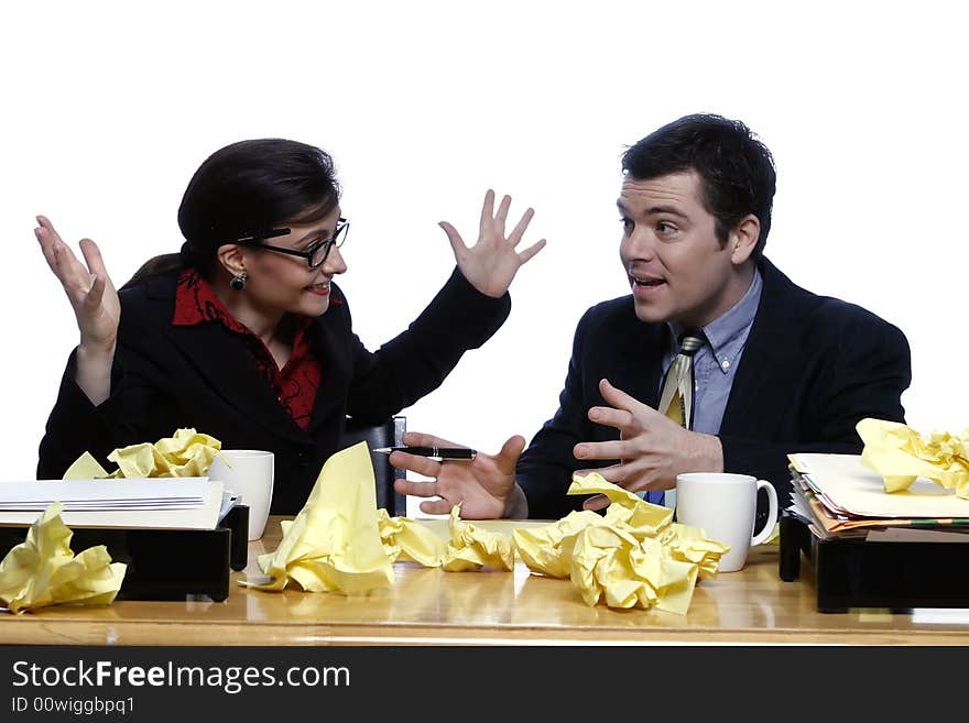 An isolated shot of a businessman and businesswoman discussing ideas at a desk, littered with yellow paper. An isolated shot of a businessman and businesswoman discussing ideas at a desk, littered with yellow paper.