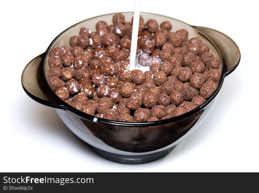 Chocolate cereal with milk in a glass bowl on white background