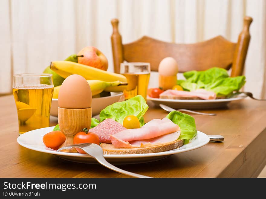 Table served with snacks. Fruits, vegetables, bread, egg, ham etc. Focus on the front egg, shallow depth of field. Table served with snacks. Fruits, vegetables, bread, egg, ham etc. Focus on the front egg, shallow depth of field.