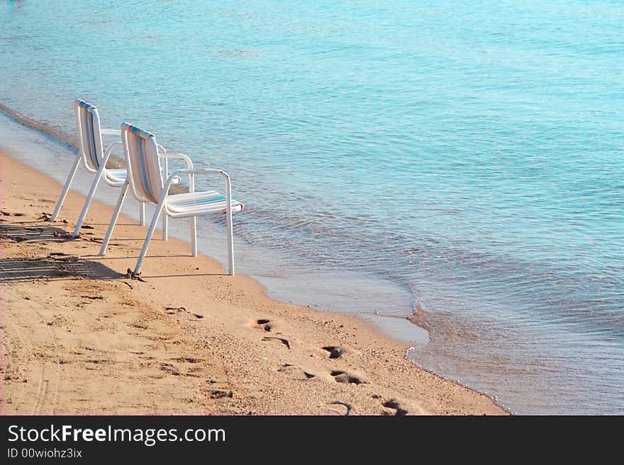 Two empty beach chairs on a lonely quite beach early in the morning. The location is at Hurghada, Egypt. Two empty beach chairs on a lonely quite beach early in the morning. The location is at Hurghada, Egypt.