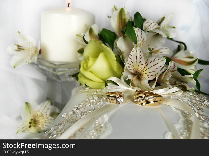 Wedding rings on a bridal pillow with bouquet and candle. Wedding rings on a bridal pillow with bouquet and candle.