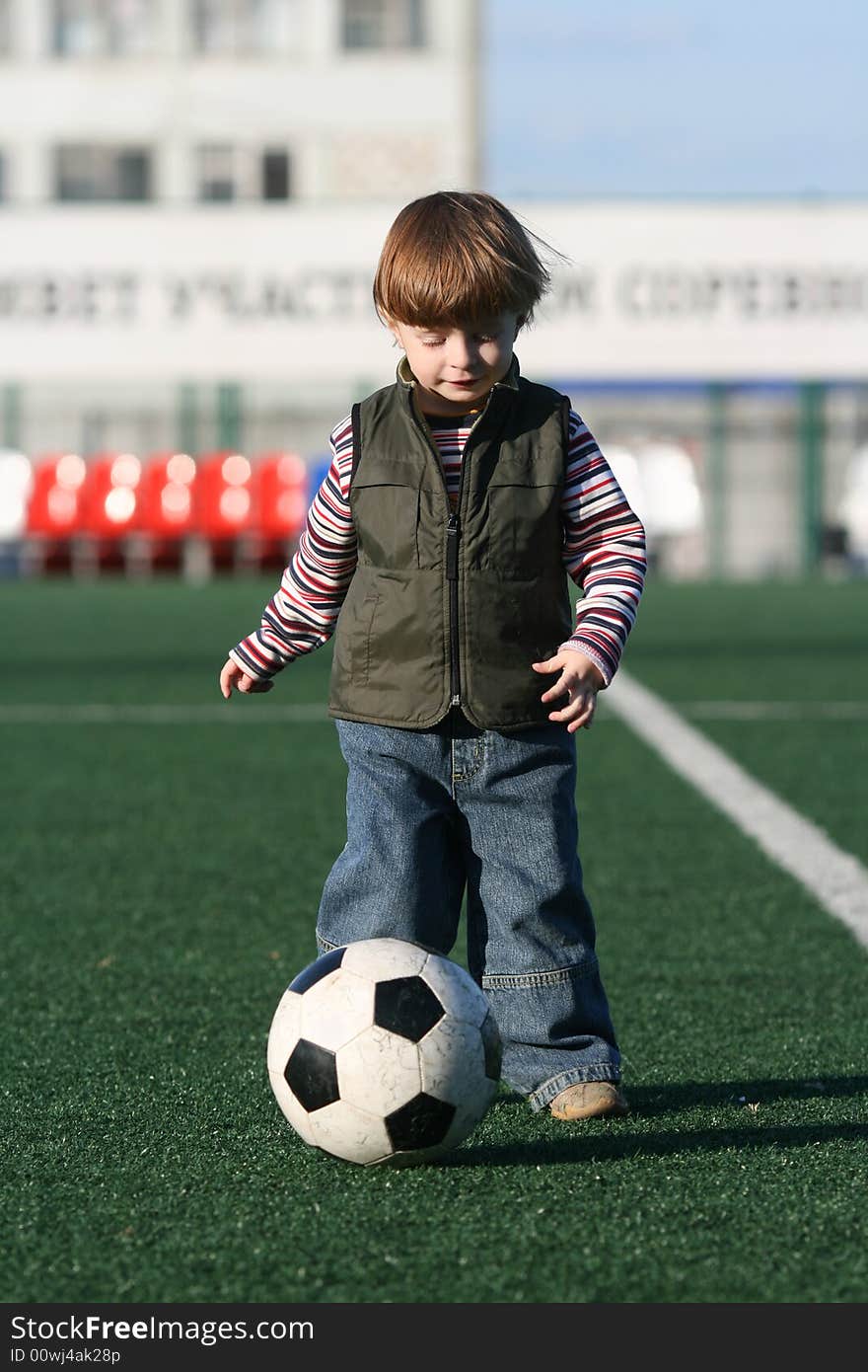 The little boy playing football in stadium. The little boy playing football in stadium