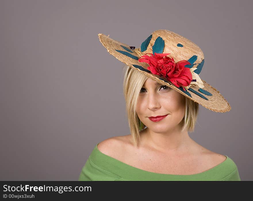 A blonde wearing a flowered straw hat with an odd look on her face. A blonde wearing a flowered straw hat with an odd look on her face.