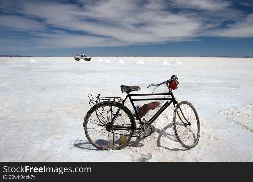 Old bike against white jeep parked on the famous Salar Uyuni landmark. Bolivia