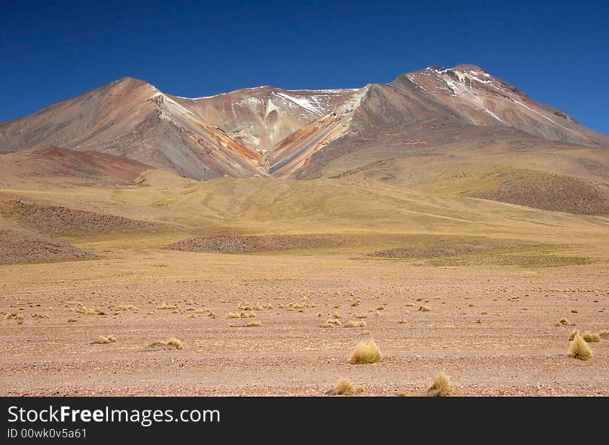 Feature land with beautiful geological feature in background. Vulcano. Altiplano. Bolivia