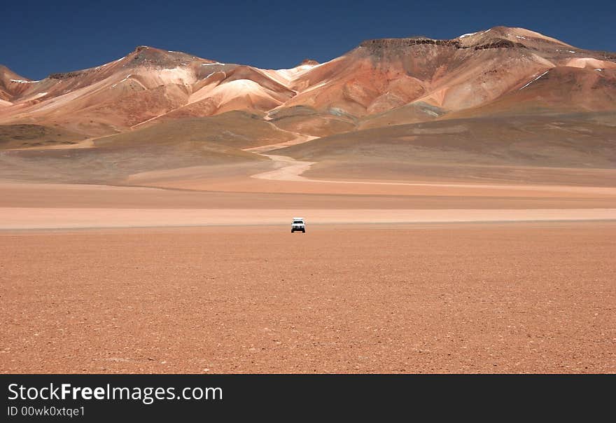 White jeep against beautiful geological feature in background. Vulcano. Altiplano. Bolivia. White jeep against beautiful geological feature in background. Vulcano. Altiplano. Bolivia