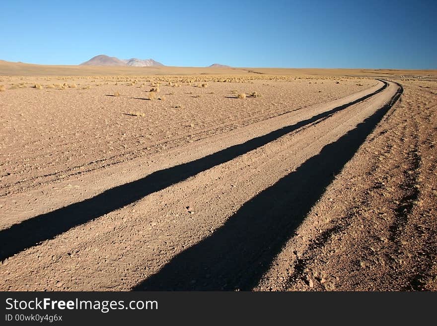 Azure clear sky over the dirt road leading to mountain range. Altiplano. Bolivia. Azure clear sky over the dirt road leading to mountain range. Altiplano. Bolivia