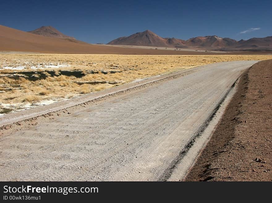 Road leading cross mountain range full of grass growing on rocky grounds. Altiplano. Bolivia. Road leading cross mountain range full of grass growing on rocky grounds. Altiplano. Bolivia.