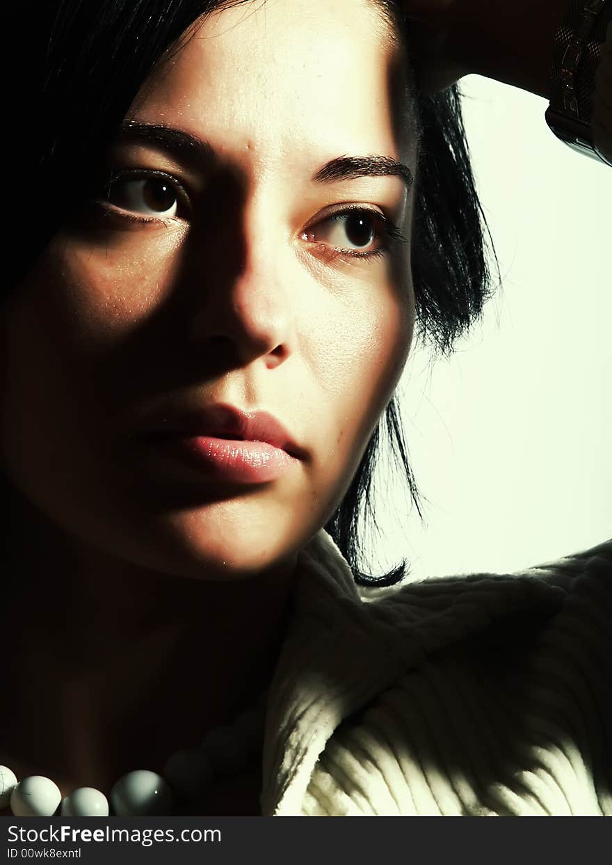 A high-key portrait about an attractive trendy lady with black hair who is looking at something and she has a glamorous look. She is wearing a white coat and a white necklace. A high-key portrait about an attractive trendy lady with black hair who is looking at something and she has a glamorous look. She is wearing a white coat and a white necklace.