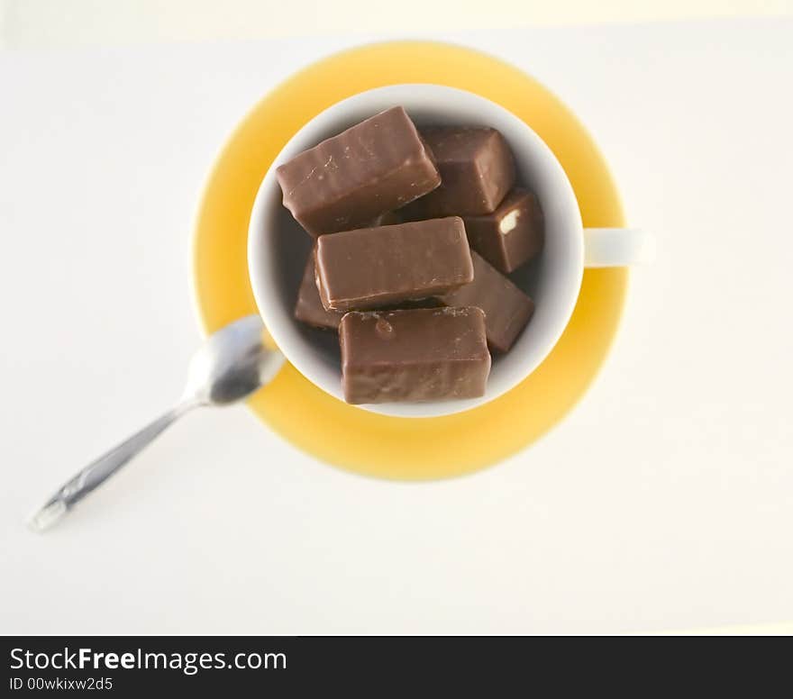 Chocolate candies in yellow cup, hot chocolate