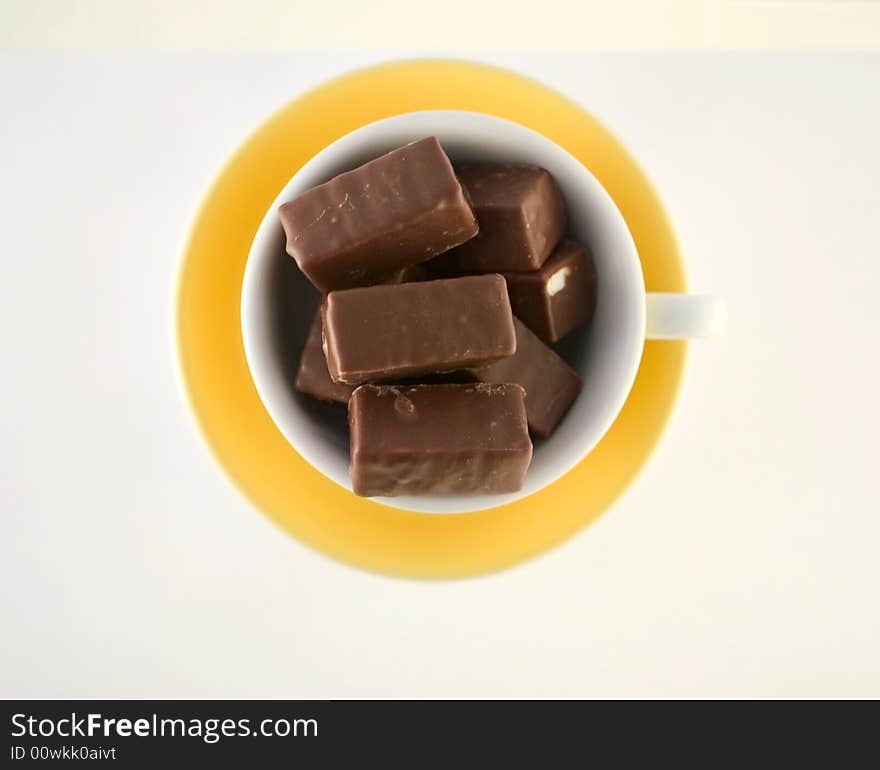 Chocolate candies in yellow cup, hot chocolate