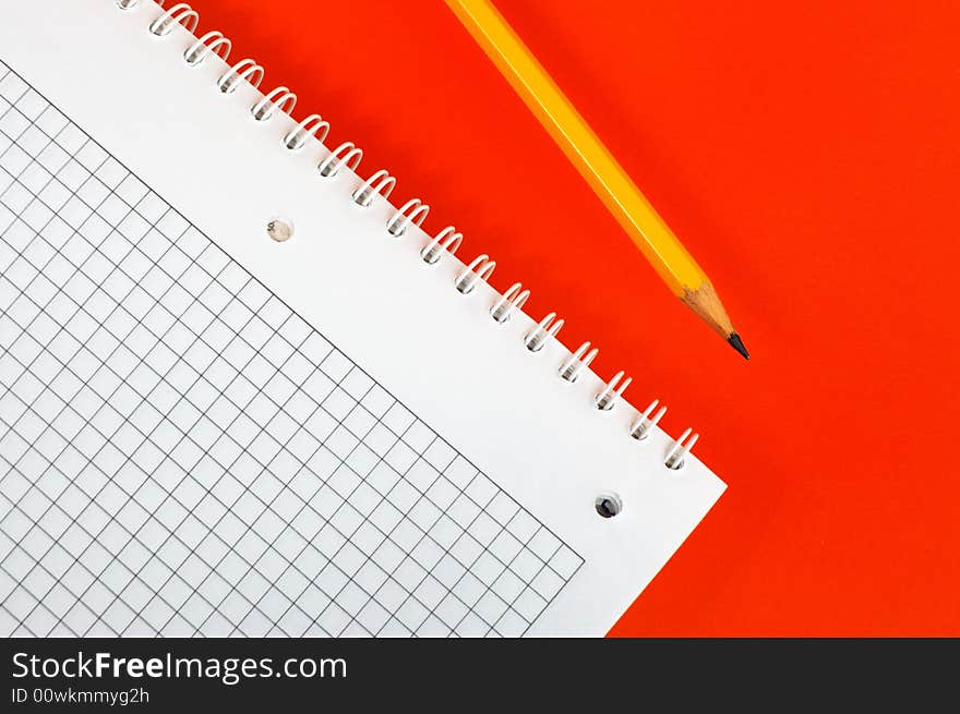 Notebook and pencil  ( on a dark red background)